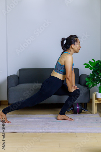 Portrait beautiful adult (40 years old) Asian woman doing Home Workout in Sports Clothing with Stretching Exercise in the room white background.