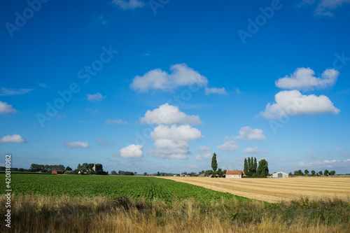 Church and farm in West Flanders Belgium under big sky with clouds © Bennekom