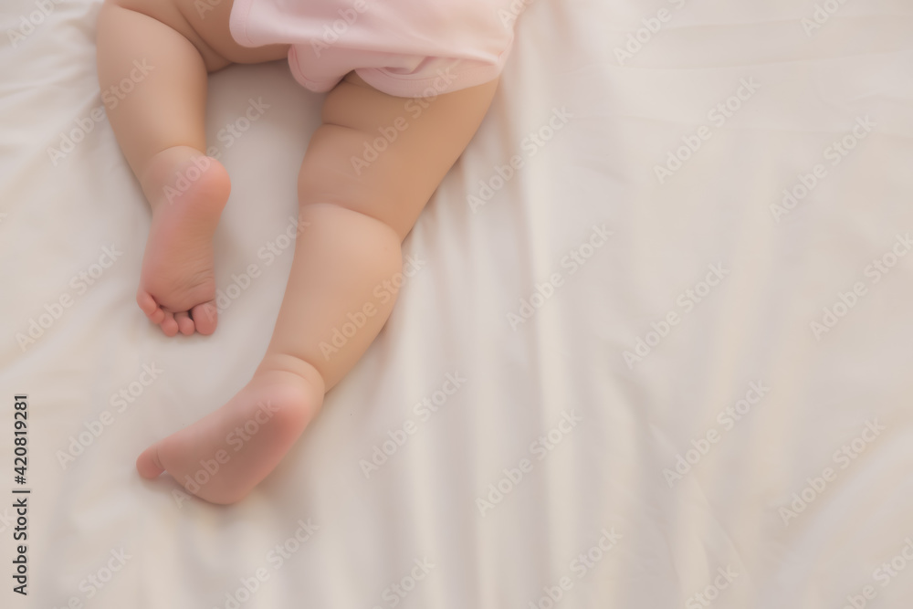 Adorable innocent baby try to crawling on bed that first time infant baby crawl Lovely toddler child wear pink baby dress. Toddler children trying to use leg for lifting legs and body Selective focus Adorable innocent baby try to crawling on bed that first time infant baby crawl Lovely toddler child wear pink baby dress. Toddler children trying to use leg for lifting legs and body Selective focus