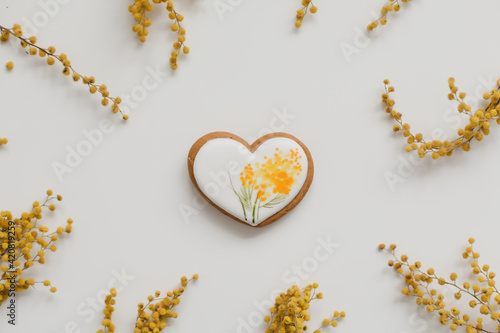 Easter gingerbread cookie and yellow mimosa florwers on white background photo