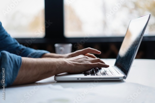 Man s hands typing on laptop keyboard.