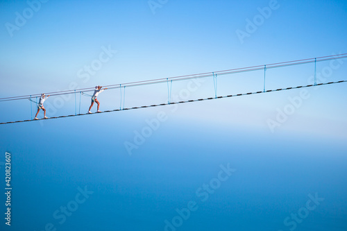 Girls crossing the chasm on the rope bridge. © travnikovstudio