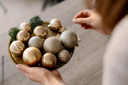 florist girl holds a tray with Christmas balls for a golden Christmas tree in her hands. Christmas tree decorations.