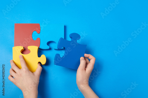 Top view hands of a autistic child arranging color puzzle symbol of awareness for autism spectrum disorder. Autism Awareness Day or month. photo