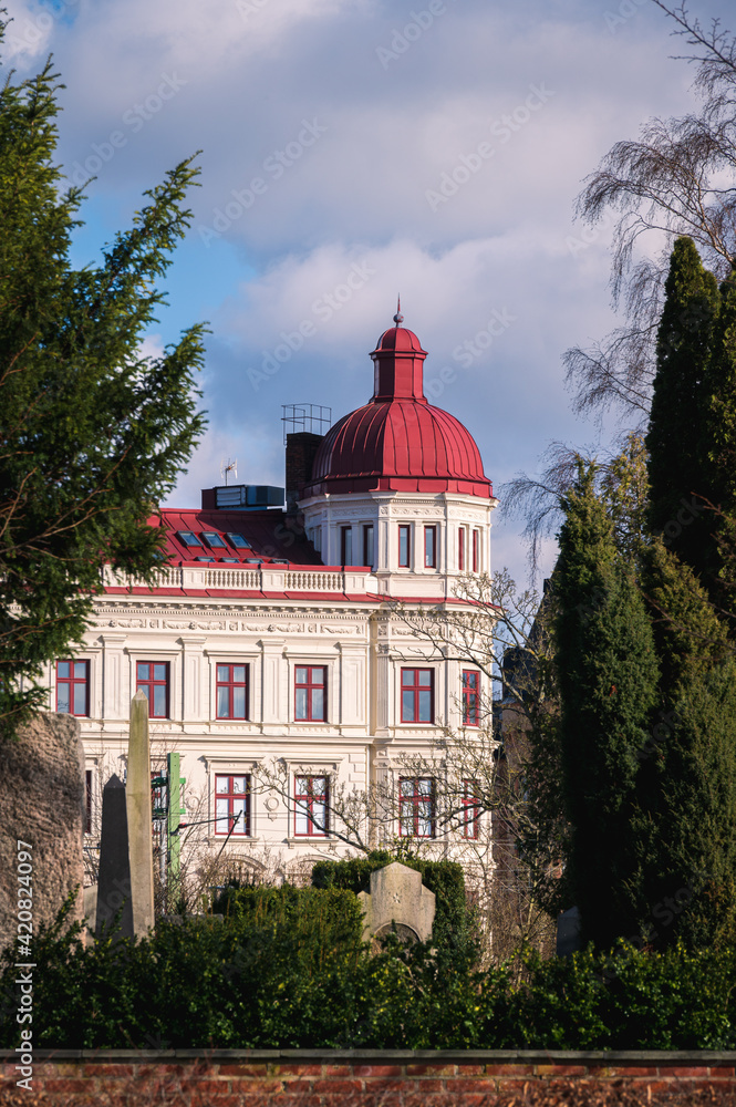 A sunlit facade of a historic building with red roof in Lund Sweden during spring sunset A sunlit facade of a historic building with red roof in Lund Sweden during spring sunset