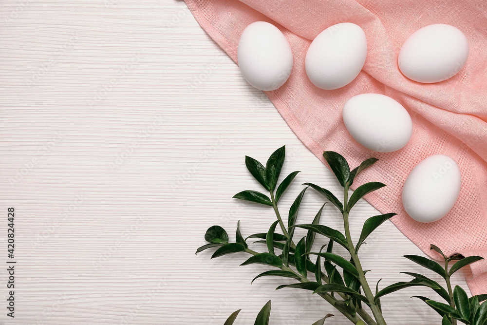 White eggs on a pink tablecloth. Tabletop texture. Green leaves. Easter plot. White eggs on a pink tablecloth. Tabletop texture. Green leaves. Easter plot.
