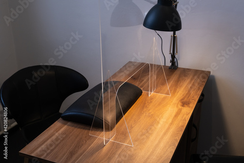 Manicure table with protective shield. Manicurist workplace with plexiglass sneeze guard for social distancing during coronavirus pandemic.