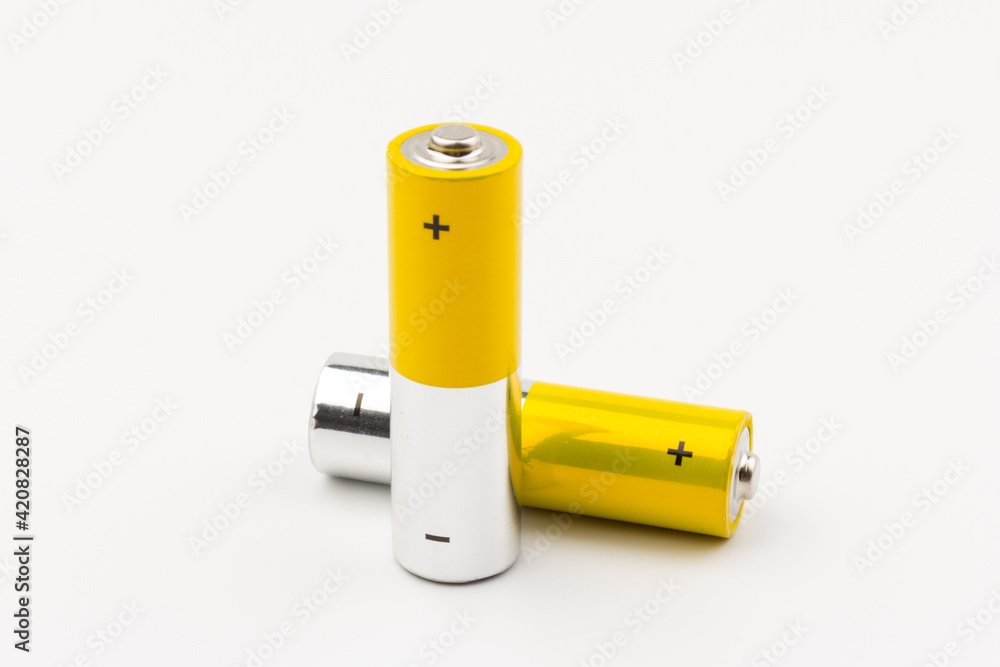 Photo of gray-yellow alkaline AA batteries on white background. Recycling of rechargeable NiMH batteries. The most popular size of accumulators. Copy space. Photo of gray-yellow alkaline AA batteries on white background. Recycling of rechargeable NiMH batteries. The most popular size of accumulators. Copy space.