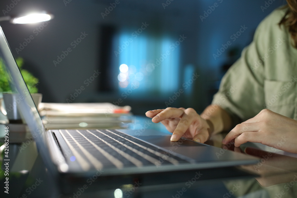 Woman hand browsing on laptop using touchpad in the night