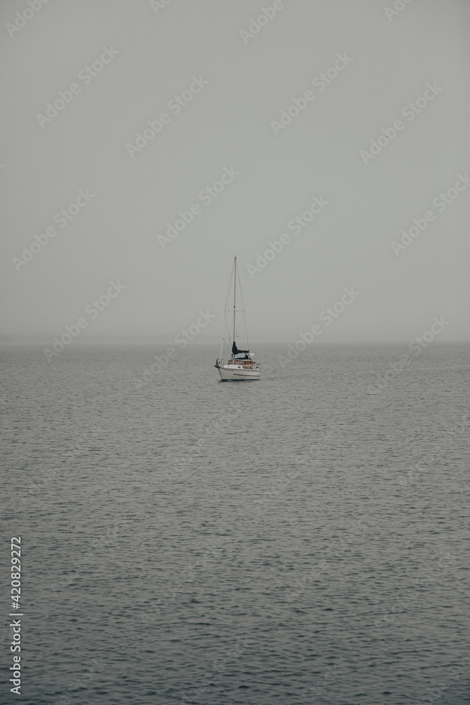 Sailboat at sea during a foggy and gloomy morning.