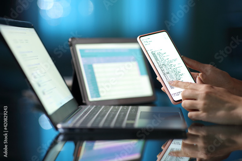 Woman hand using multiple devices at home in the night photo