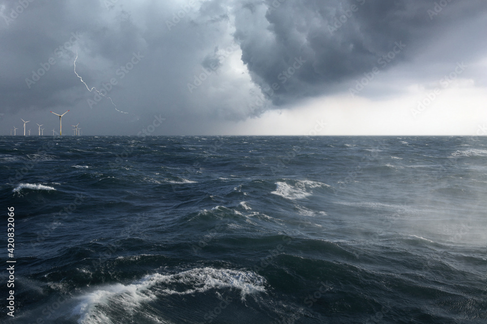 Ein Offshore Windpark mit aufgewühlter See in einem Sturm mit Blitz
