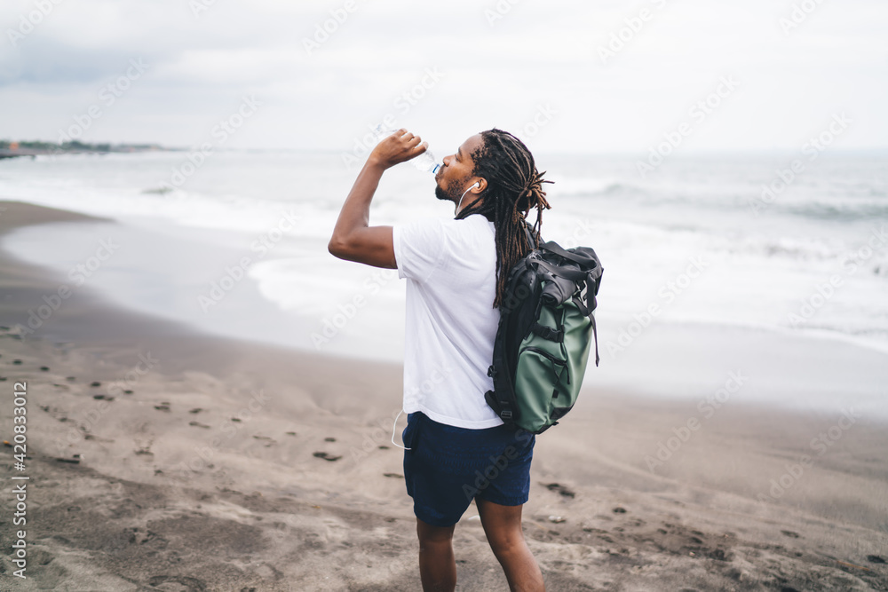 Ethnic man with backpack on beach Ethnic man with backpack on beach