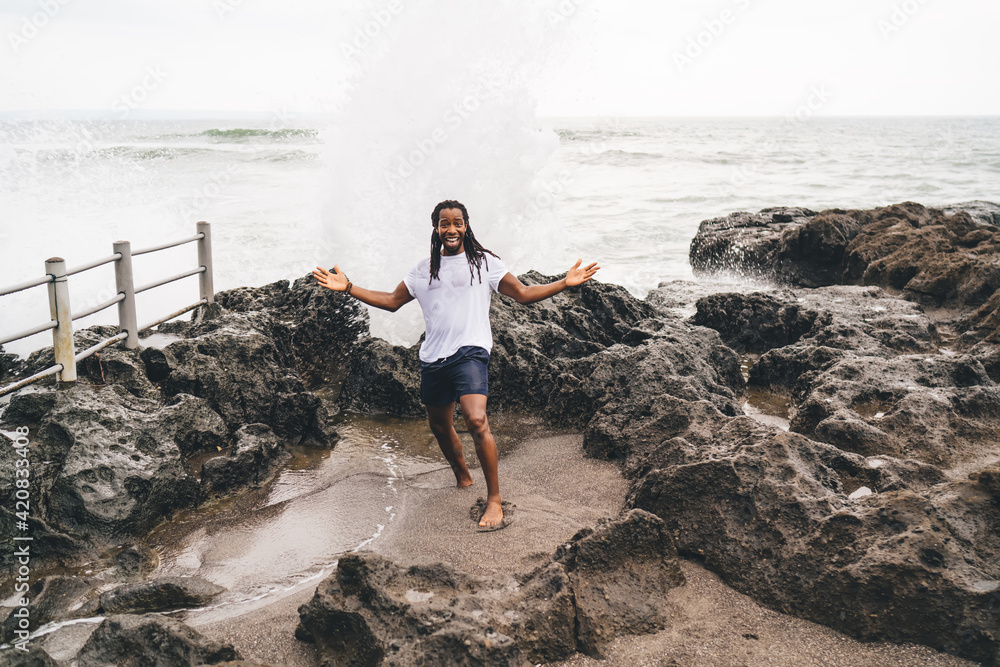 Content black man on rocky shore