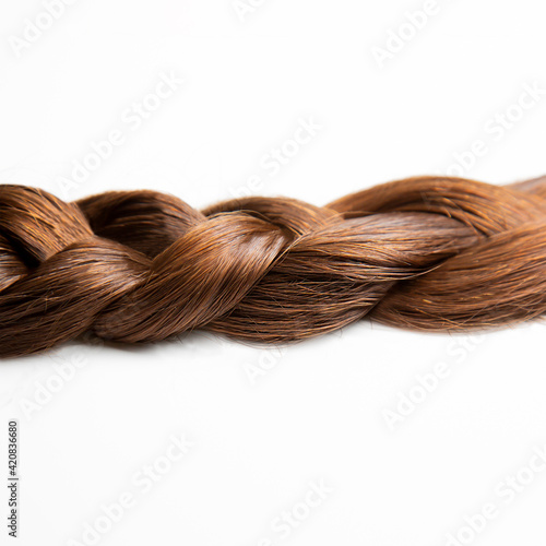 A braid of dark brown hair on a white background. Top view. Close-up. Hair style. Brown hair: chestnut. Hair care.