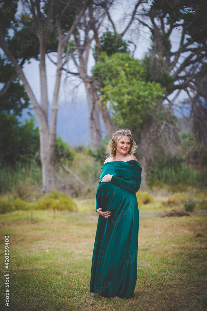 Close up image of a pregnant woman in a beautiful green dress in nature Close up image of a pregnant woman in a beautiful green dress in nature