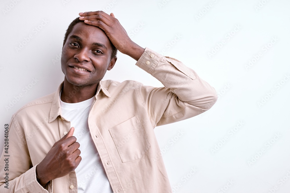 Pleasant afro american guy touching head and smiling Pleasant afro american guy touching head and smiling