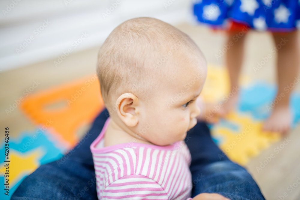 Adorable baby sitting between the feet of her father Adorable baby sitting between the feet of her father