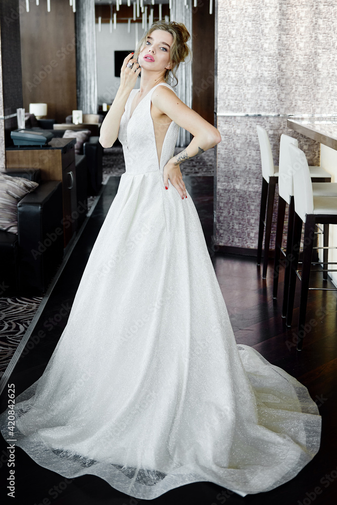 Portrait of beautiful bride wearing fashion wedding dress with luxury make-up and hairstyle indoors. Wedding concept