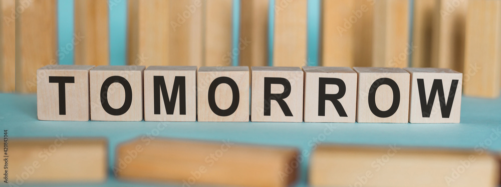 Word TOMORROW made from wooden cubes on a light background. Word TOMORROW made from wooden cubes on a light background.