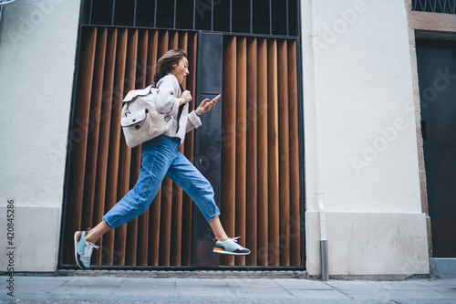 Foto Stylish lady using smartphone while rushing and running along pavement