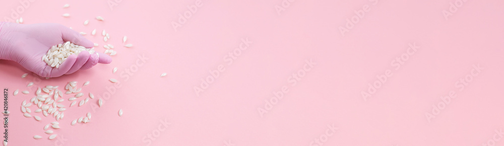 Horizontal banner with hand in rubber gloves with hair removal wax beads on pink background. Film Wax Granules. Sugaring concept with copy space. Top view