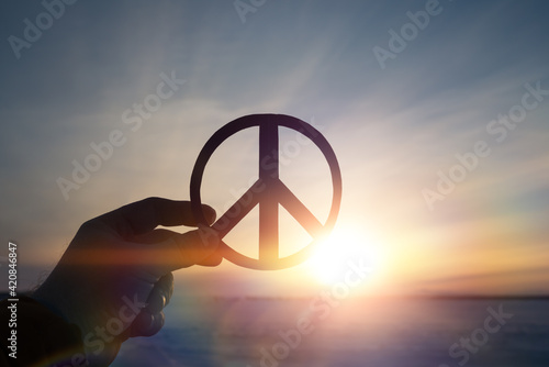 Peace sign symbol in the hand of a man on the background of the sunset. photo