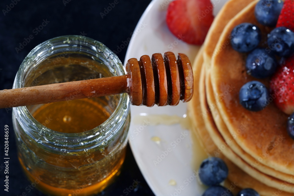 Pancakes with blueberries, strawberries, honey on a blue background Pancakes with blueberries, strawberries, honey on a blue background
