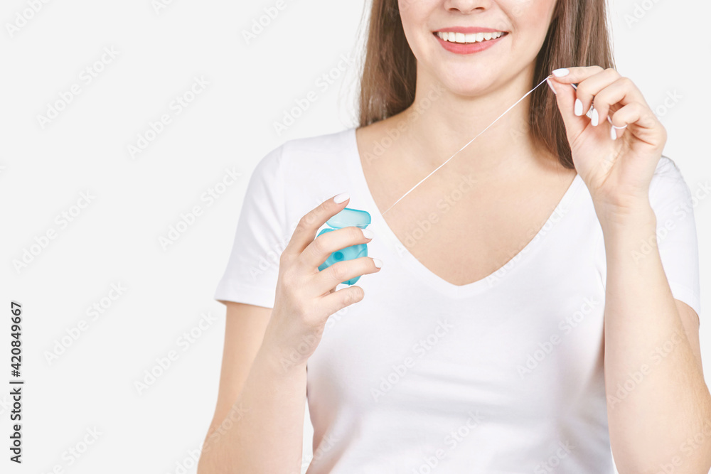 Young woman holding teeth floss. Dental health care concept. Beauty smiling face. Adult mouth everyday routine. Toothache cleaning. Orthodontist whitening Young woman holding teeth floss. Dental health care concept. Beauty smiling face. Adult mouth everyday routine. Toothache cleaning. Orthodontist whitening