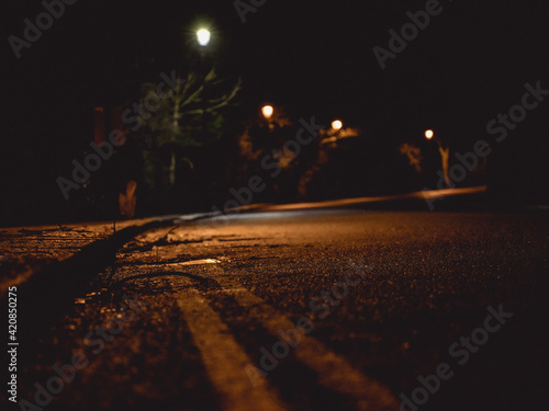 Dark moody curved village road at night with streetlights