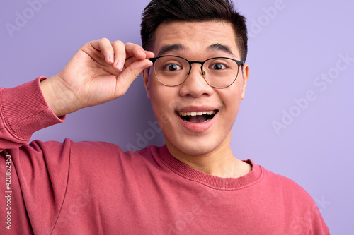 close-up portrait of nice chinese male in eyeglasses emotionally reacts on something  with opened mouth