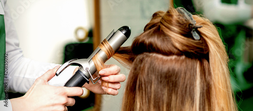 Hairdresser curling hair with curling iron