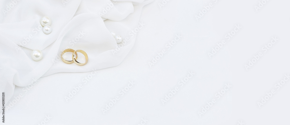 Two golden wedding rings and pearls on white background. Wedding banner Two golden wedding rings and pearls on white background. Wedding banner