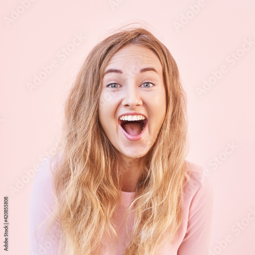 Pretty young woman amazed by sale news. Happy female person outdoors. Summer cute portrait. Lady blonde long hair. Cute adult student at town. Pink background. Copyspace. Wow female emotion