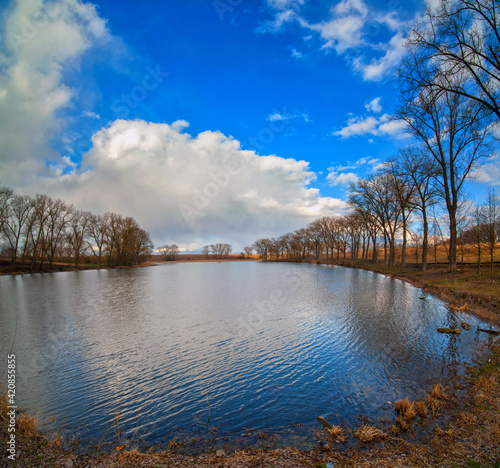landscape with pond, and reflection in water beautiful sky, dry reeds and ear...
