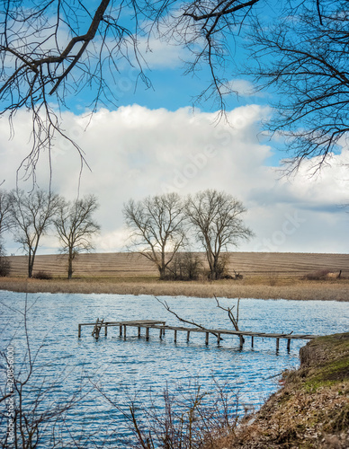 bridge pier and trees on the shores of a small lake in early spring