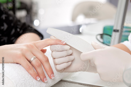 closeup of female hand getting nail manicure by professional manicurist