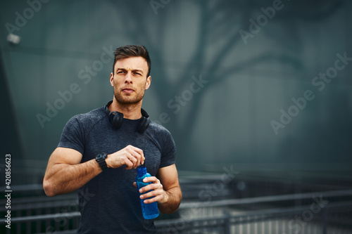Young handsome men resting after jogging in the city and open a bottle of water