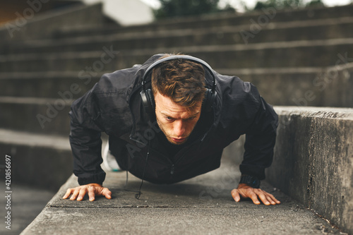 Young fit man doing push-ups outdoors on concrete steps