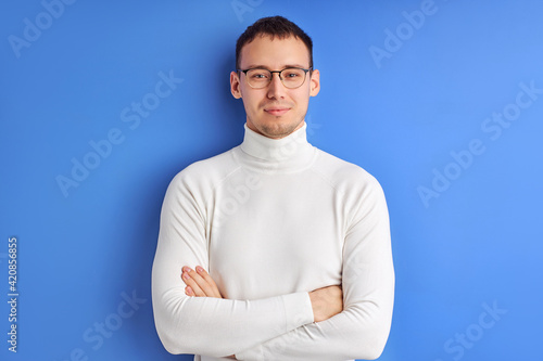 Young businessman in spectacles posing looking at camera with arms folded