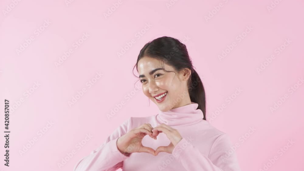 Beauty concept of 4k Resolution. Asian woman doing heart shape hand making on pink background. Beauty concept of 4k Resolution. Asian woman doing heart shape hand making on pink background.