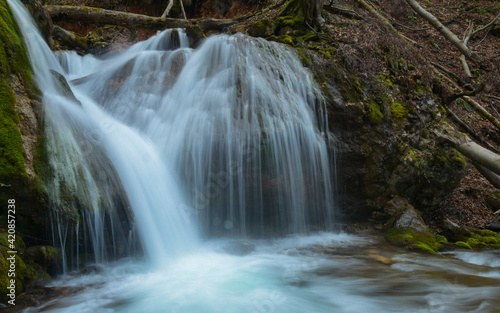 A massive waterfall flowing through large mossy stones and boulders. Spring season  Sureanu Mountains  Carpathia  Romania