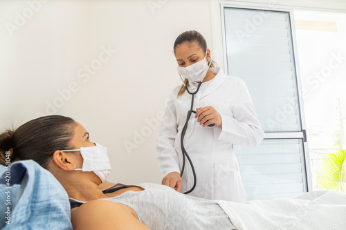 Female doctor measuring pressure of patient with mask.