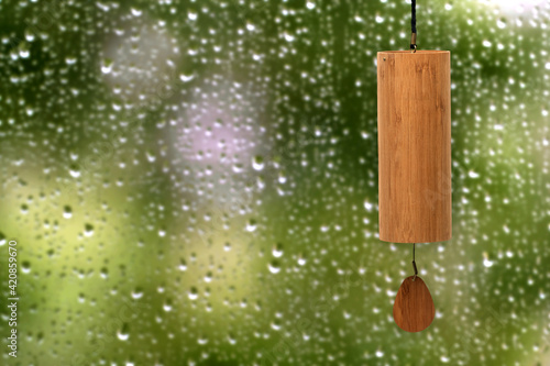 Fotografi Close-up of a hand made Koshi chime musical instrument made from bamboo on a blurred natural green background during a rainy summer day