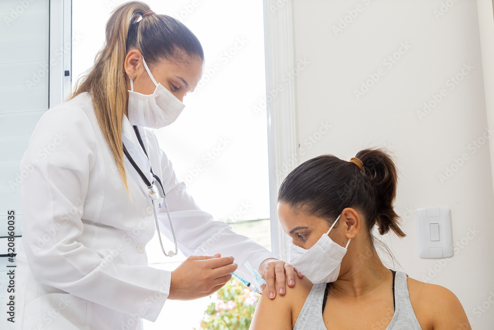 Doctor wearing a mask and applying vaccine to a patient in a mask. Doctor wearing a mask and applying vaccine to a patient in a mask.