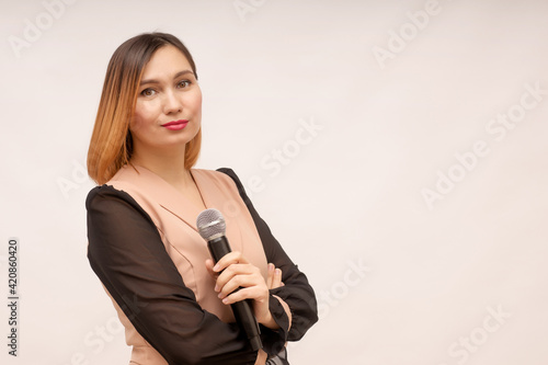 Young woman stands with a microphone in her hands on a white background