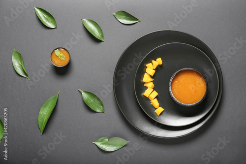 Composition with bowl of mango sauce on dark background
