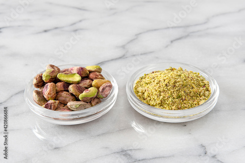 Small pile of pistachios in a saucer, whole shelled and powdered
