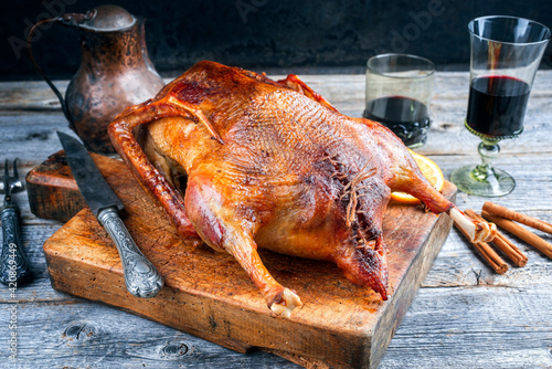 Traditional roasted stuffed Christmas goose with orange slices served as close-up on an old rustic wooden board photo