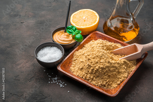 Mustard powder and ingredients on a brown background with space to copy.
